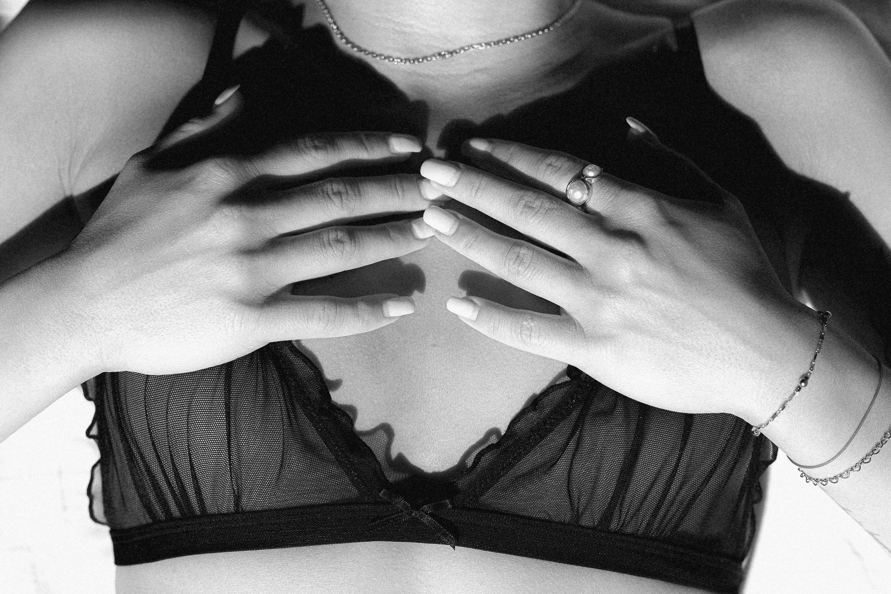 Person wearing a black bra with hands covering the chest area