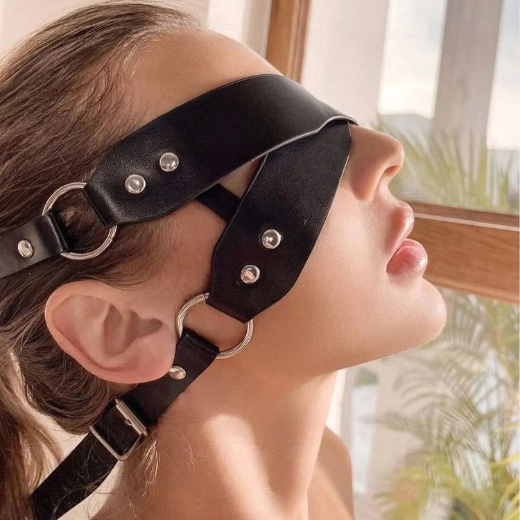 Angled side view of a woman wearing a the themis vegan leather BDSM blindfold with metal hardware, featuring an elegant and comfortable fit.